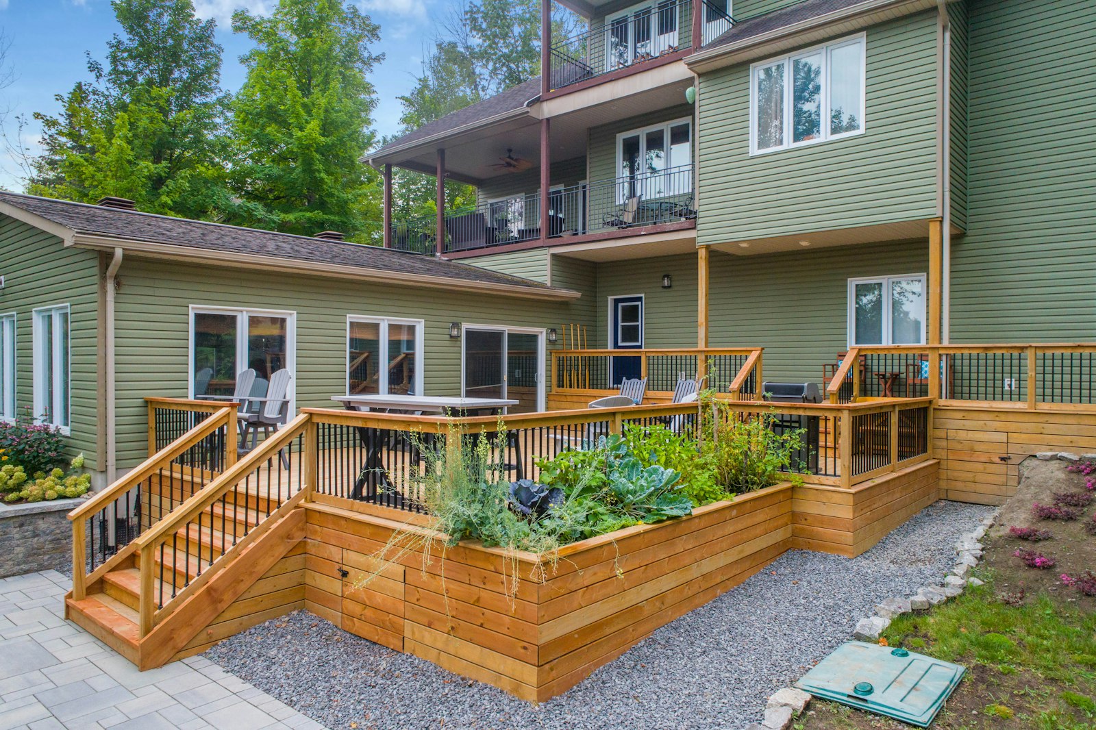 Multi-level wood deck and paver patio with outdoor seating behind a home