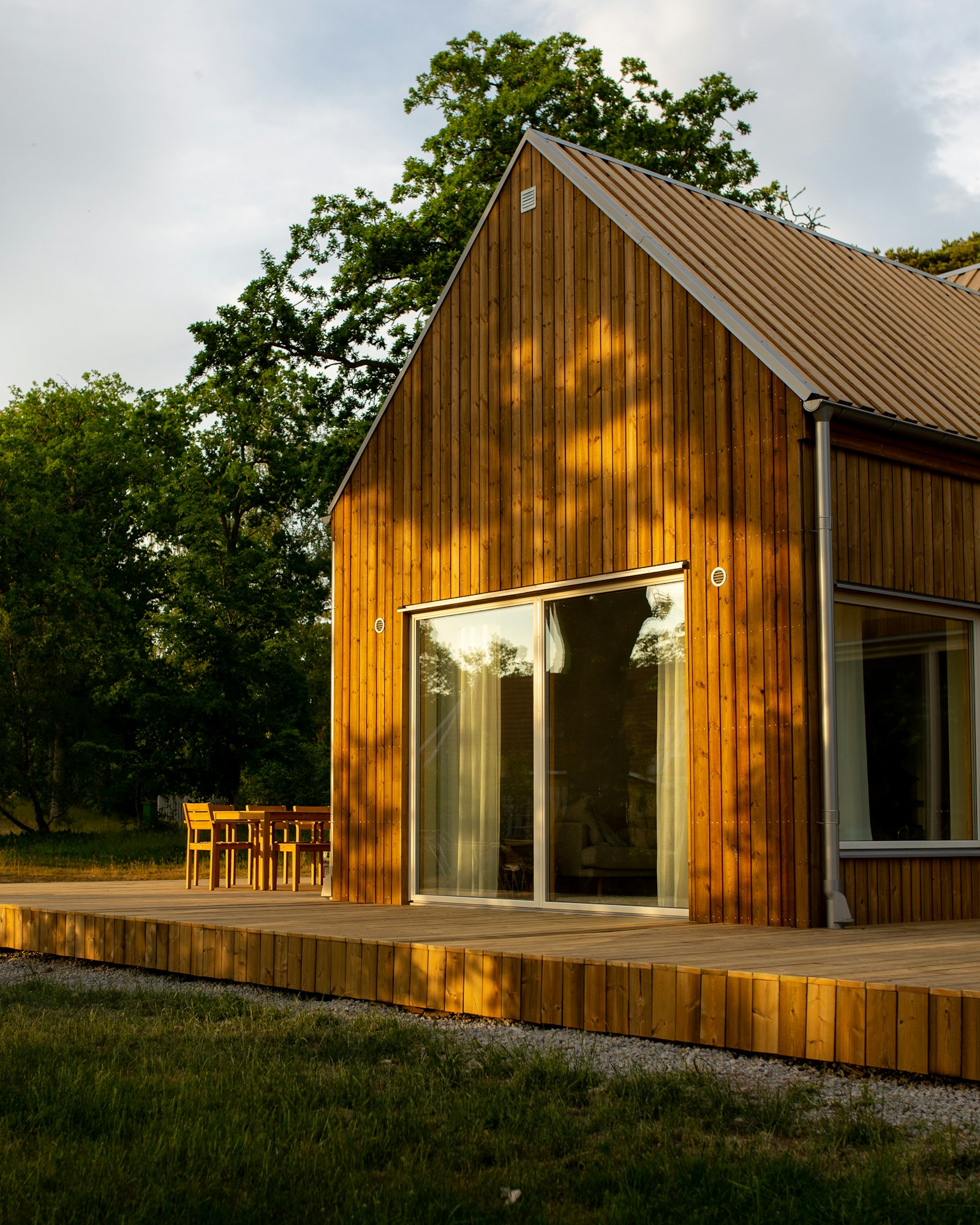 Converted barn-style home with wood siding, large windows, and a wraparound deck